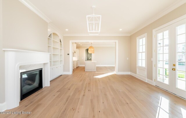 unfurnished living room featuring french doors, built in shelves, light hardwood / wood-style floors, and ornamental molding