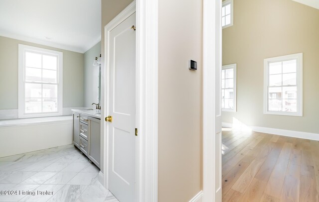 corridor with light hardwood / wood-style flooring and sink