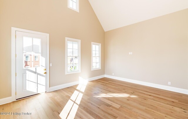 spare room featuring high vaulted ceiling and light hardwood / wood-style floors