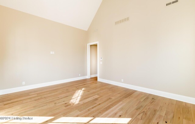 empty room with light wood-type flooring and high vaulted ceiling