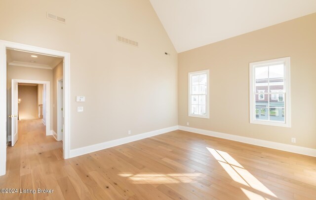 empty room featuring high vaulted ceiling and light wood-type flooring