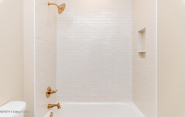 bathroom featuring toilet and tiled shower / bath combo