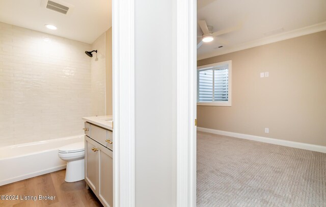 full bathroom featuring hardwood / wood-style floors, toilet, tiled shower / bath combo, ceiling fan, and vanity