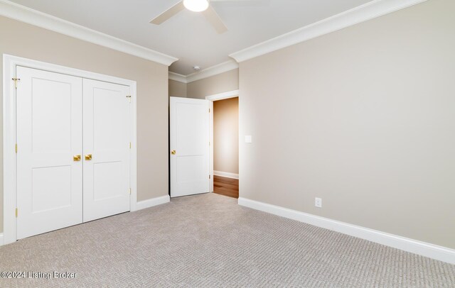 unfurnished bedroom with a closet, ceiling fan, carpet, and crown molding