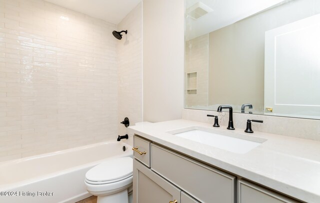 full bathroom featuring tiled shower / bath combo, vanity, and toilet