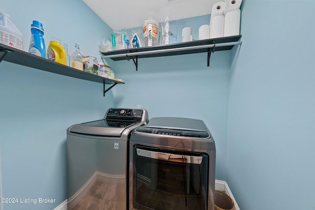 clothes washing area with laundry area, baseboards, and washer and clothes dryer