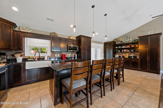 kitchen with dark countertops, stainless steel microwave, a sink, and visible vents