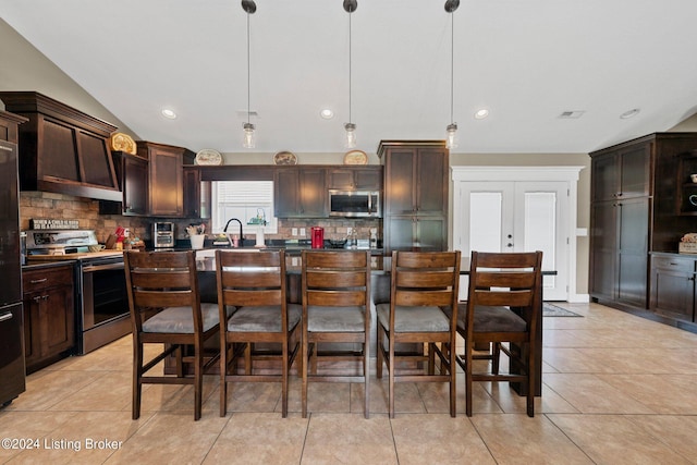 kitchen featuring dark brown cabinetry, a kitchen bar, stainless steel appliances, and decorative backsplash