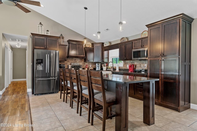 kitchen featuring a center island, a breakfast bar area, stainless steel appliances, visible vents, and dark brown cabinets