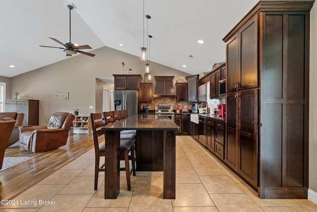 kitchen with dark brown cabinetry, light tile patterned flooring, stainless steel appliances, and open floor plan