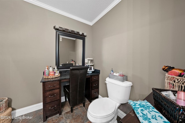 bathroom featuring crown molding, toilet, stone finish flooring, vanity, and baseboards