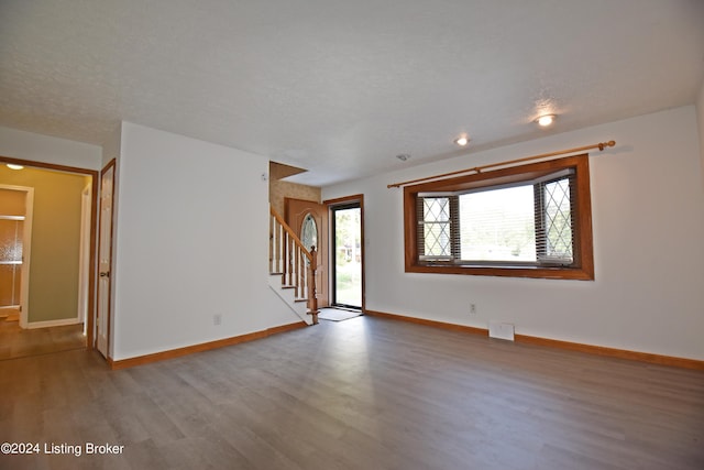 unfurnished room featuring wood-type flooring and a textured ceiling