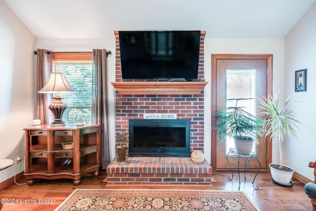 living room featuring wood-type flooring and a brick fireplace