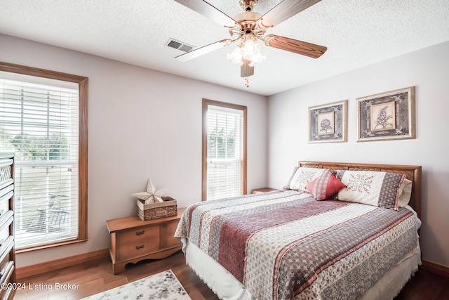 bedroom featuring a textured ceiling, ceiling fan, and dark hardwood / wood-style floors