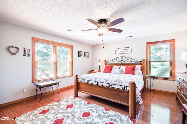 bedroom with a textured ceiling, dark wood-type flooring, and ceiling fan