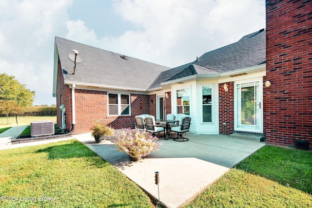 rear view of property with a yard, a patio, and central air condition unit