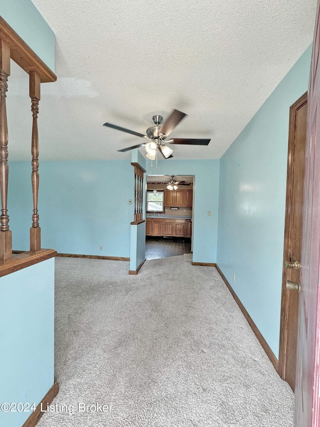 unfurnished living room featuring a textured ceiling, carpet flooring, and ceiling fan