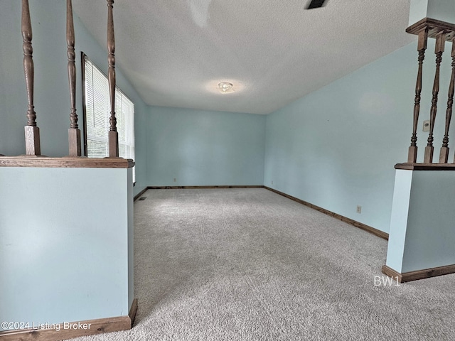 empty room with a textured ceiling and carpet flooring