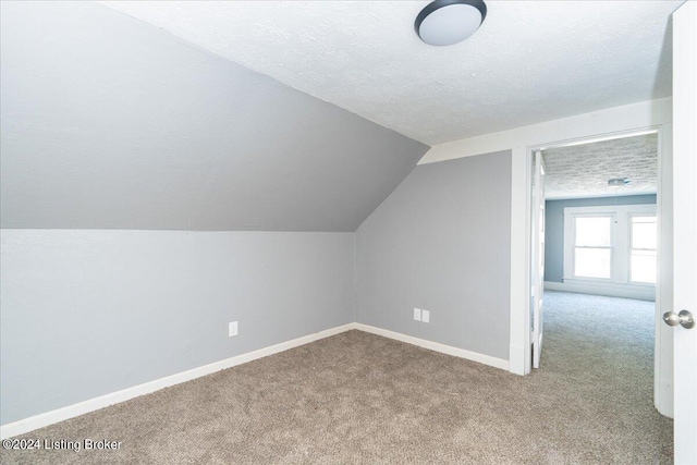 bonus room with light carpet, a textured ceiling, and vaulted ceiling