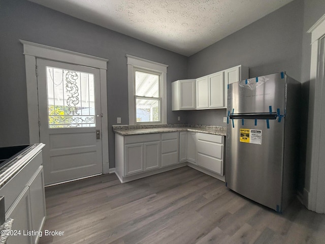 kitchen with stainless steel fridge, white cabinets, dark hardwood / wood-style floors, and a textured ceiling