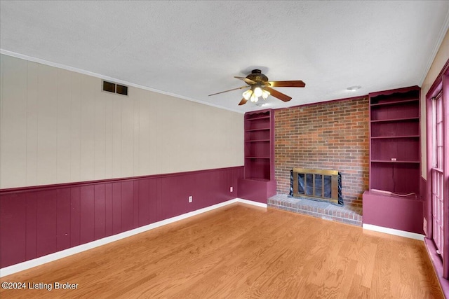 unfurnished living room featuring built in shelves, ceiling fan, hardwood / wood-style floors, and a textured ceiling