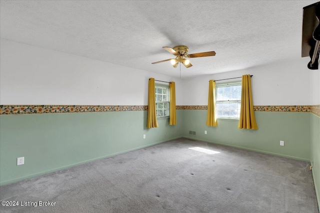 empty room with carpet flooring, ceiling fan, and a textured ceiling