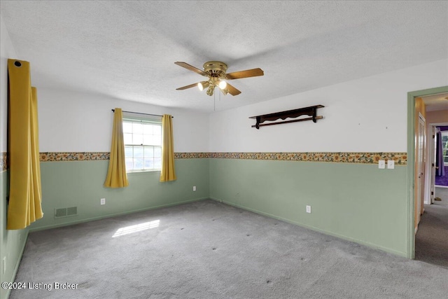 carpeted empty room with ceiling fan and a textured ceiling