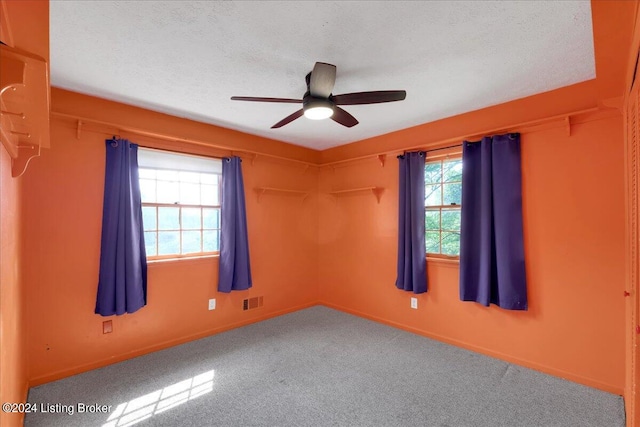 empty room featuring a textured ceiling, ceiling fan, and carpet flooring