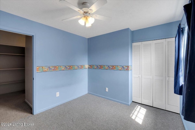 unfurnished bedroom with a closet, a textured ceiling, ceiling fan, and carpet