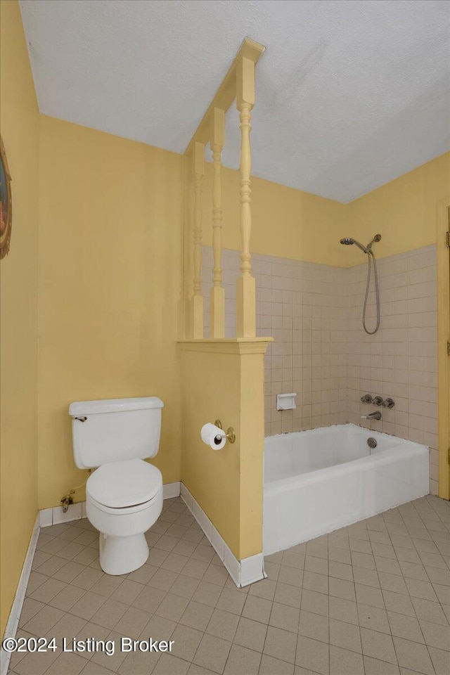 bathroom featuring tile patterned flooring, toilet, tiled shower / bath combo, and a textured ceiling