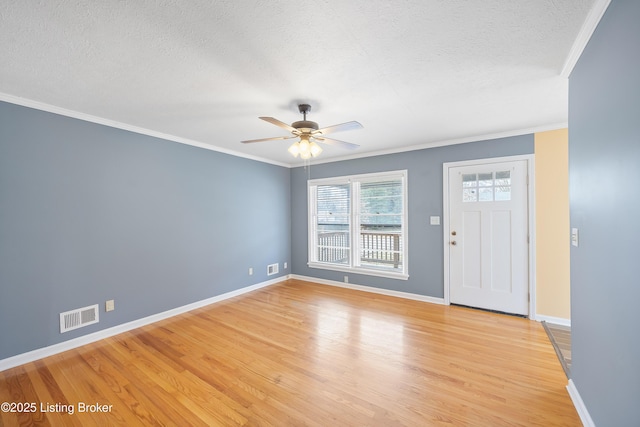 foyer entrance with ceiling fan, ornamental molding, a textured ceiling, and light wood-type flooring