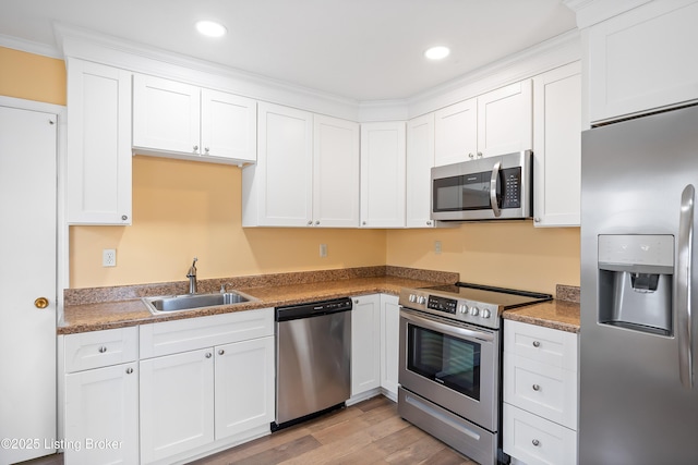 kitchen featuring white cabinetry, sink, light hardwood / wood-style floors, and appliances with stainless steel finishes