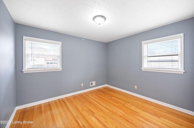 empty room with hardwood / wood-style flooring and a healthy amount of sunlight