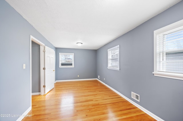 empty room featuring a textured ceiling and light hardwood / wood-style floors