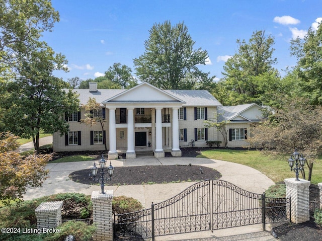 greek revival inspired property featuring a fenced front yard, a chimney, a gate, and a front yard