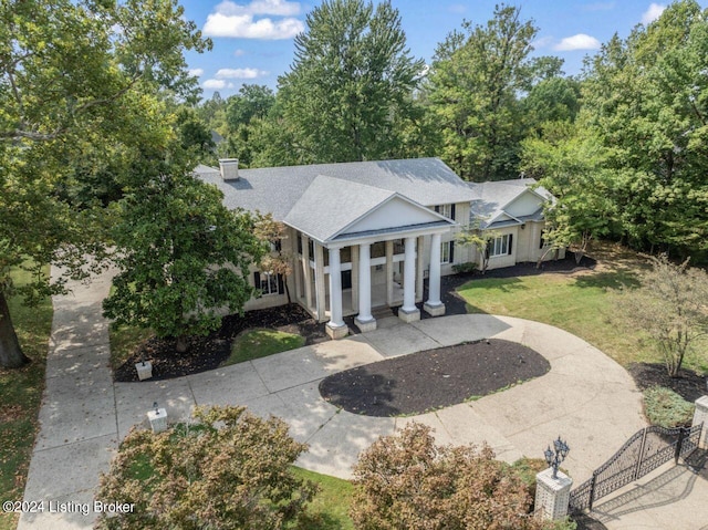 greek revival house with roof with shingles, concrete driveway, and a front yard