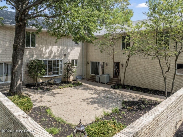 back of property with entry steps and brick siding