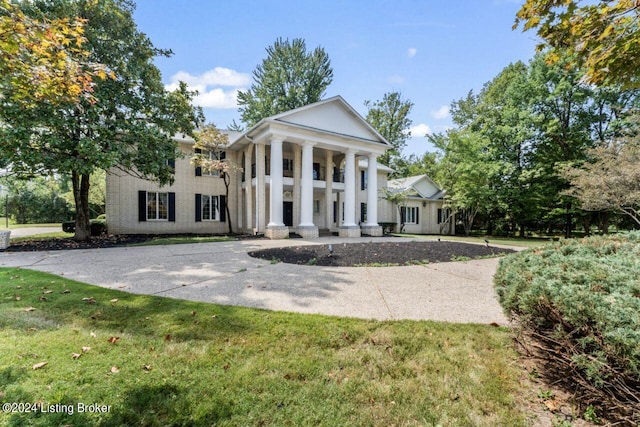 greek revival inspired property with a porch, a front yard, and driveway