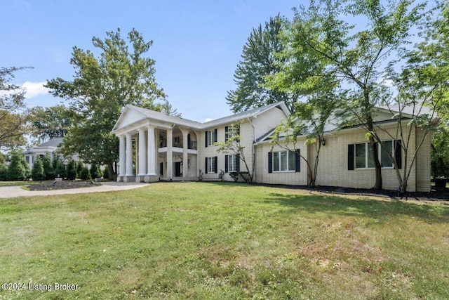 neoclassical / greek revival house featuring brick siding and a front yard