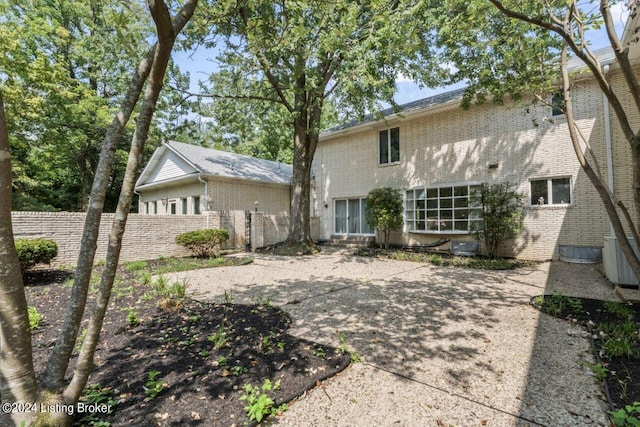 rear view of property featuring fence and brick siding