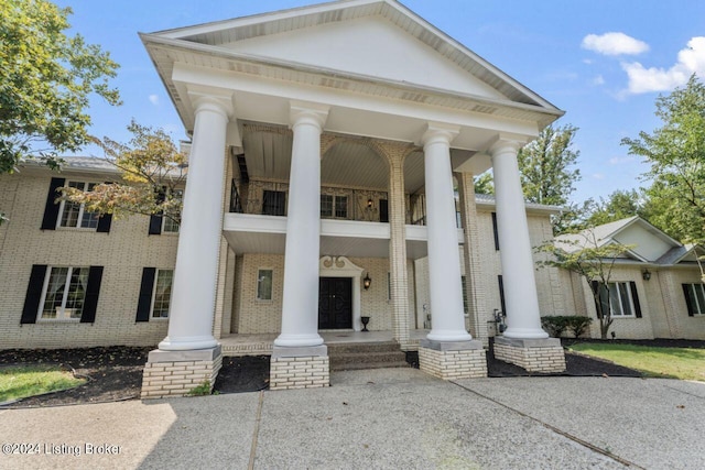 view of front of home with a porch, brick siding, and a balcony