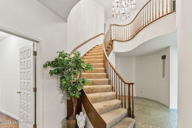 stairs featuring a notable chandelier, a towering ceiling, and baseboards