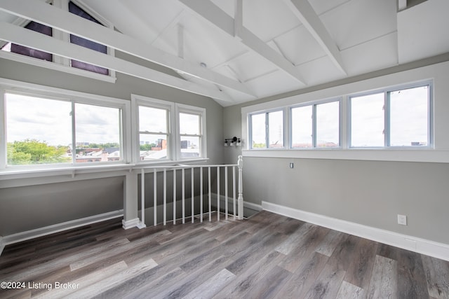 empty room with hardwood / wood-style flooring and vaulted ceiling with beams