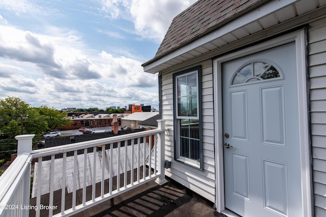 entrance to property with a shingled roof and a balcony