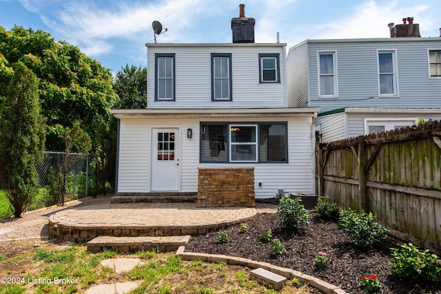 rear view of house with a fenced backyard, a chimney, and a patio