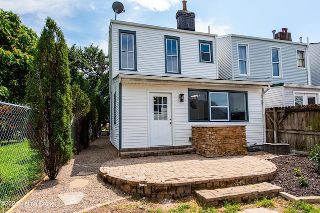 rear view of house with a chimney, a patio area, and a fenced backyard