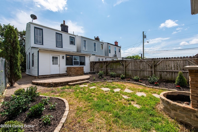 rear view of property featuring a fenced backyard, a patio, and a chimney