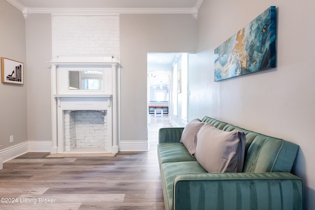 living room featuring wood-type flooring, a fireplace, and crown molding