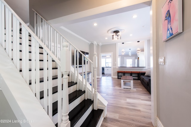 staircase with hardwood / wood-style floors and ornamental molding