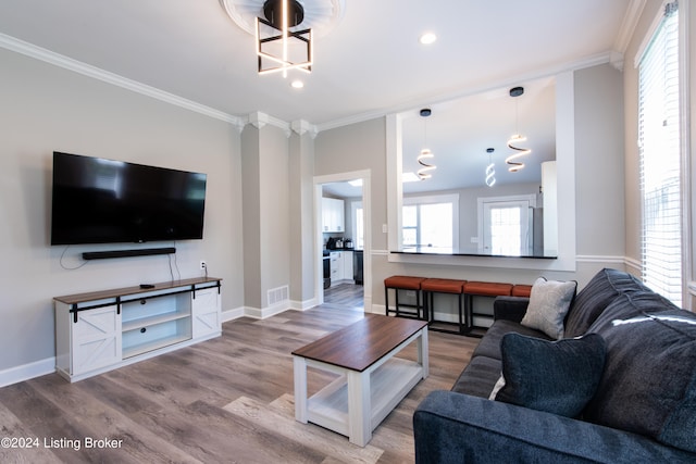 living room with crown molding, wood-type flooring, and an inviting chandelier